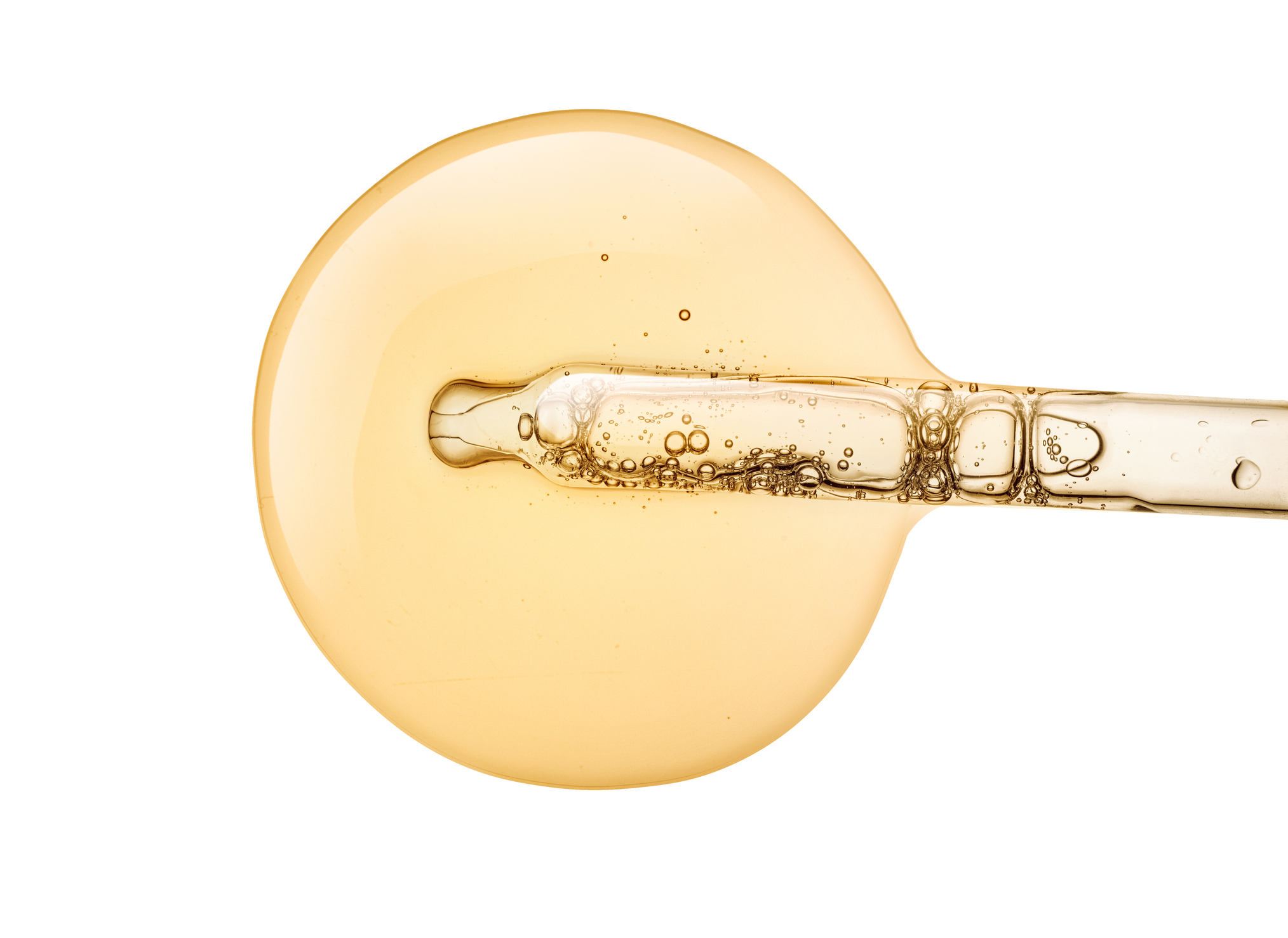 Liquid yellow gold gel or serum with a pipette on white isolated background